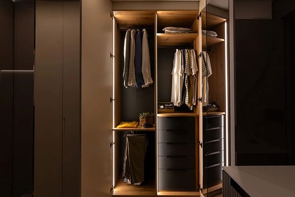 Armario empotrado con iluminación interior y distribución de estantes y barras para ropa