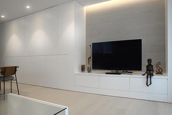 Armarios empotrados blancos en salón moderno con mueble de televisión