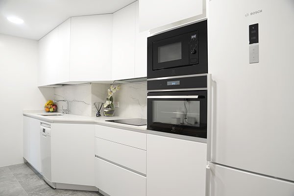 Cocina blanca con electrodomésticos integrados y encimera de mármol