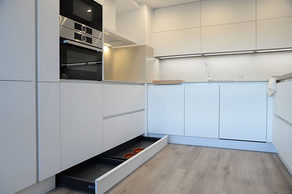Cocina minimalista con cajones extraíbles y muebles blancos