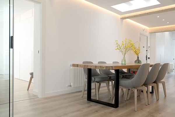 Comedor con suelo laminado en tono claro y mesa de madera