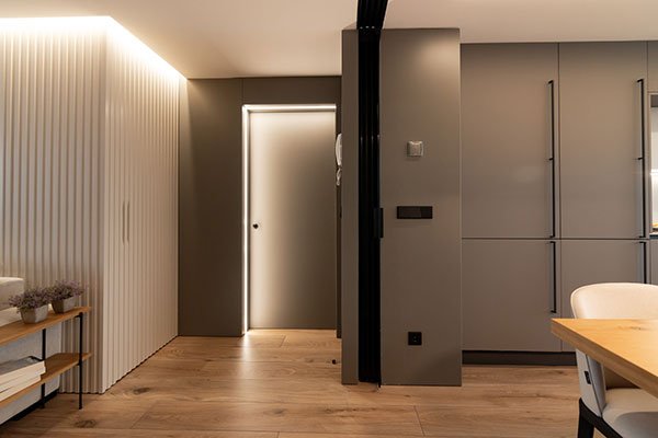 Puerta gris interior con iluminación perimetral en salón contemporáneo