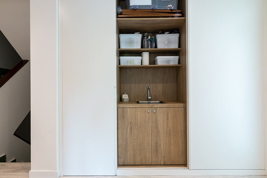 Mueble a medida con estantes de madera, fregadero y puertas blancas correderas